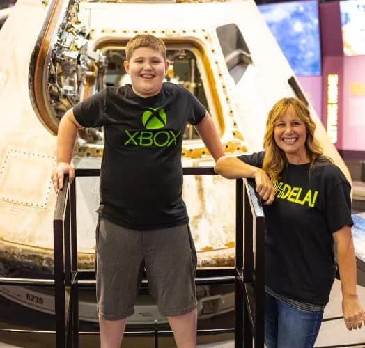 A student and an OHDELA teacher in front of a space capsule at a museum